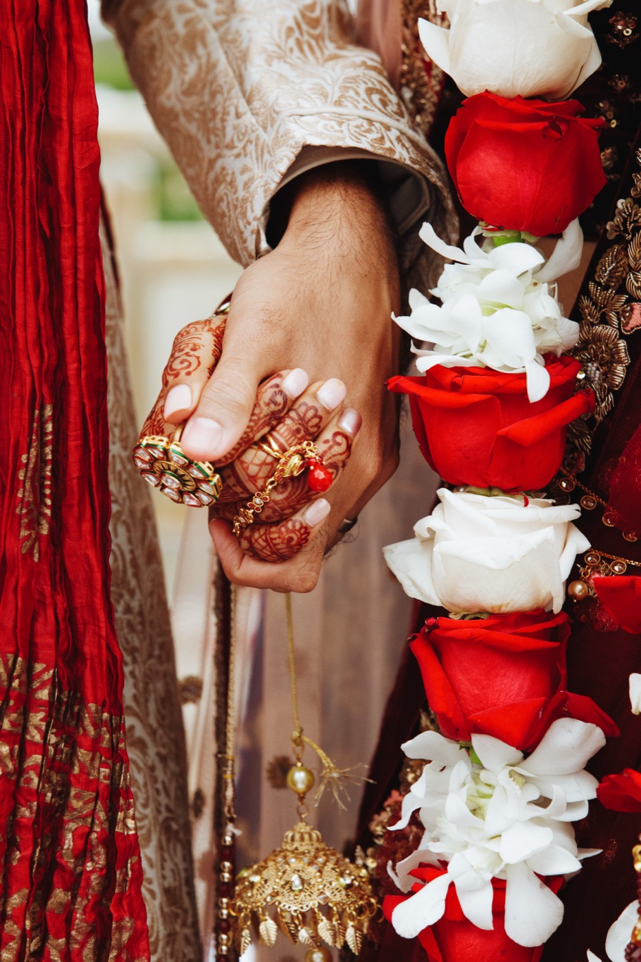Candid wedding photography — a bride and groom holding hands in traditional attire