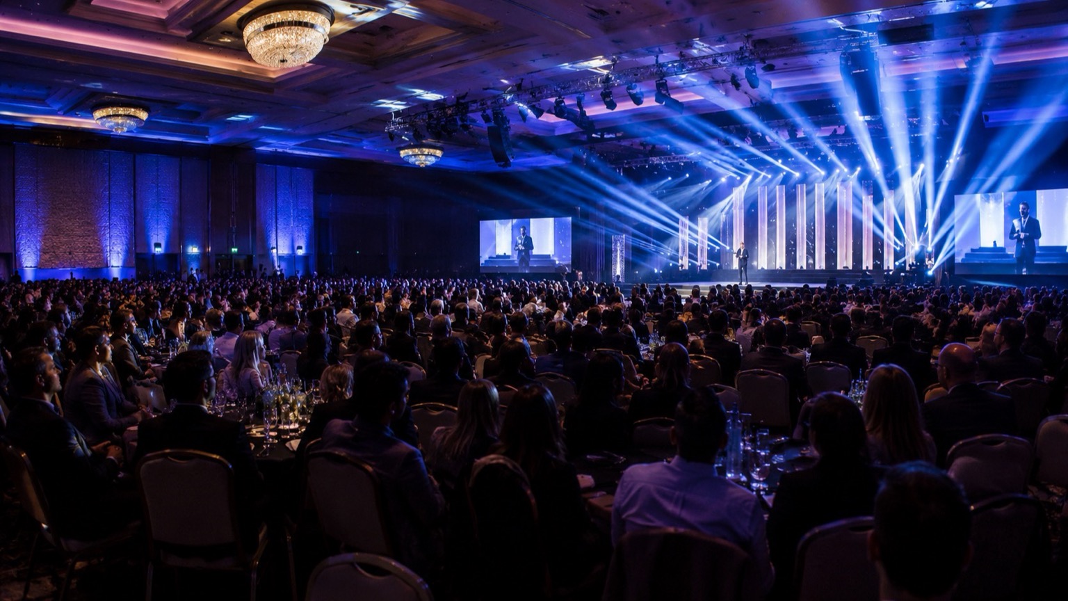 Event photography in Delhi — a speaker on a brightly lit stage at a corporate conference with an engaged audience