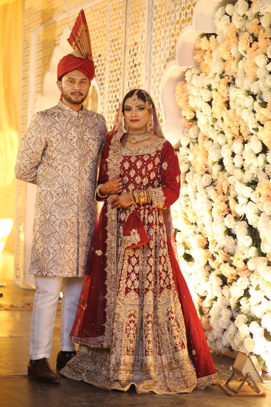 Indian wedding ceremony — a bride and groom in traditional wedding attire on a floral stage